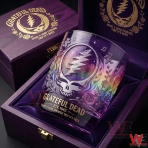 A close up view of a Grateful Dead whiskey glass with multicolor cosmic artwork placed inside a purple wooden gift box with soft interior lining and engraved band themed details!