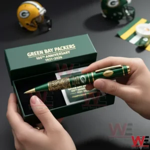 Hands holding a premium Green Bay Packers pen with gold detailing above an open green gift box with anniversary text and a matching card with football themed items in the background!