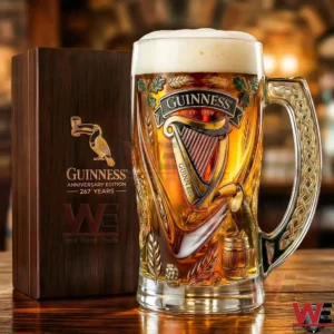 A Guinness anniversary beer glass next to a wooden presentation box!