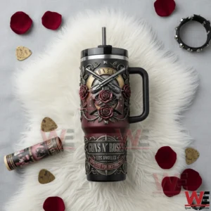 Top down view of a Guns N Roses insulated tumbler with handle and straw on a white furry surface surrounded by red rose petals guitar picks a small bottle and a bracelet!