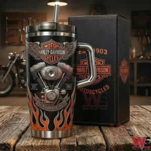 Harley Davidson Motorcycles 1903 Yeti Tumbler 4 Harley Davidson insulated tumbler with handle and straw displayed next to a branded gift box on a rustic wooden surface in a workshop!