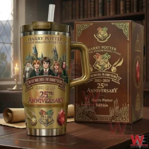 Gold Harry Potter anniversary tumbler with a handle and straw displayed next to a decorative collector edition gift box on a wooden table in a library setting!