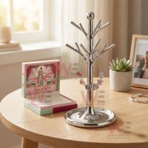 Adjustable charm bracelet on a metal jewelry tree stand with pastel gift box and desk decor including a plant and framed photo in the background.