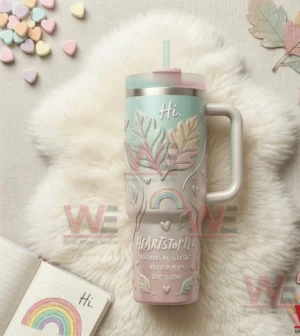 Pastel insulated tumbler with handle and straw featuring leaf heart and rainbow designs on a soft fluffy background!