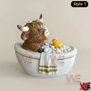 A decorative highland cow figure soaking in a bathtub with bubble accents and a small duck displayed on a neutral background!