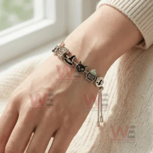 Adjustable charm bracelet on a wrist with Hocus Pocus themed charms including black cat witch hat spell book cauldron and flying witch charm!