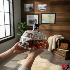 A camper van shaped whiskey bottle filled with amber liquid held by hands in a modern living room with wooden decor and framed wall art!