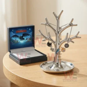 Silver adjustable charm bracelet with dragon wing flame and symbol charms hanging on a jewelry tree stand beside an open How To Train Your Dragon gift box.