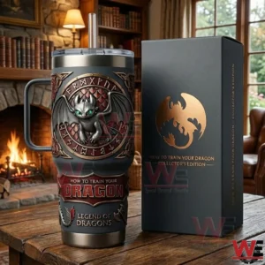 Dark insulated tumbler with a dragon emblem and straw beside a collector box on a wooden table with a fireplace background!