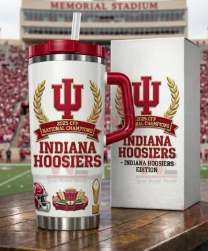 An insulated championship tumbler with Indiana Hoosiers branding gold laurel details and football themed graphics placed on a table with a stadium background!