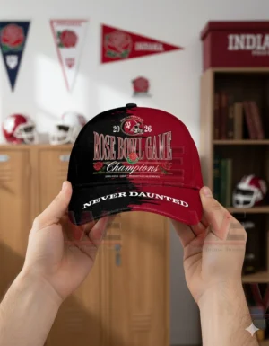 Hands holding a two tone red and black Indiana Hoosiers cap with Rose Bowl Game Champions embroidery year two thousand twenty six and Never Daunted text in a sports themed room!