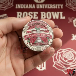 Close up of a hand holding an Indiana University 2025 Rose Bowl Champions coin with trophy and rose design against a red Rose Bowl background!