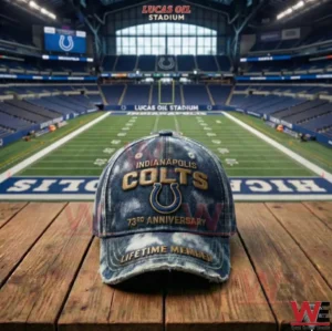 An Indianapolis Colts anniversary cap resting on a wooden table with a green football field and stadium seating visible in the background!