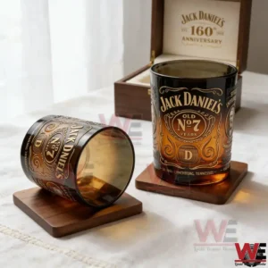 Two Jack Daniels Old No 7 anniversary whiskey glasses with engraved gold details resting on wooden coasters next to a wooden display box!