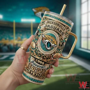 A hand holds a Jacksonville Jaguars insulated tumbler decorated with ornate design elements team logo and historical details on a football field backdrop!