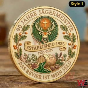 A gold edged commemorative Jagermeister coin with a deer emblem oak leaves herbal details and anniversary text displayed upright on a wooden surface!