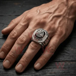 Jelly Roll Beautifully Broken Tour Bad Apple Crew Ring 4 A hand wearing a large championship style ring with a dark faceted gemstone face Jelly Roll lettering a crowned skull icon and a border of sparkling stones.