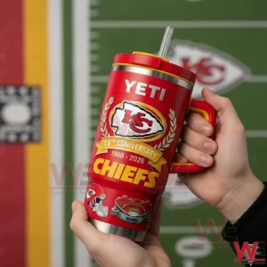 Hands holding a red Kansas City Chiefs tumbler with handle and straw showing yeti text arrowhead logo laurel wreath and 66th anniversary 1960 2026 Chiefs design with a Chiefs field background