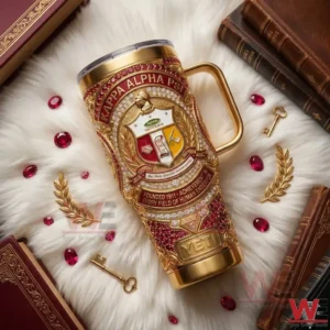 Red and gold metal tumbler with a fraternity crest lying on a soft surface with books and decorative elements!