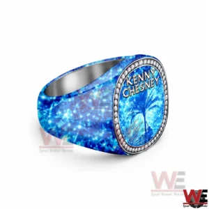 Kenny Chesney No Shoes No Shirt No Problems Luxury Ring 5 Angled view of a thick blue gemstone textured ring with an oval face reading KENNY CHESNEY above a palm tree beach scene surrounded by diamond like stones on a white background!