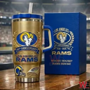 LIMITED EDITION LOS ANGELES RAMS 90TH ANNIVERSARY GOLD TUMBLER (1936-2026) 3 Gold Los Angeles Rams insulated tumbler with blue handle and straw placed beside a blue gift box with Rams logo and 90th anniversary 1936 to 2026 text on a wooden table!