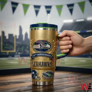 Hand holding a gold Seattle Seahawks anniversary insulated tumbler with blue lid and green handle in a football stadium setting!