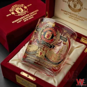 A detailed close up of a Manchester United commemorative glass inside a red velvet presentation box featuring ornate anniversary artwork!
