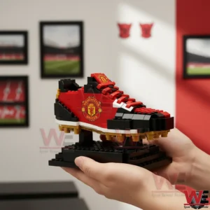 A close side view of a Manchester United building block soccer boot displayed on a black stand with club colors!