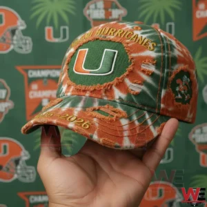 Hand holding a green and orange baseball cap with embroidered logo distressed fabric and sports themed backdrop!