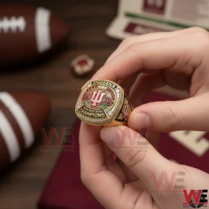 Indiana Hoosiers Rose Bowl 2026 Championship Custom Ring 7 Hands holding a gold Indiana championship ring with the IU logo and gemstones while football themed items appear in the background.