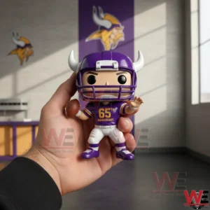 A hand holding a purple Vikings themed vinyl football figure with horned helmet and 65th anniversary jersey in front of a Vikings logo wall.