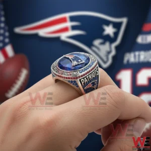 A Patriots championship ring with a blue gemstone displayed on a hand with team colors and logo visible in the background!