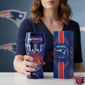 Blue and red commemorative New England Patriots beer glass with anniversary graphics standing next to a matching decorative box on a white table.