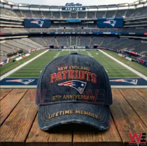 A New England Patriots anniversary cap resting on a wooden table with a green football field and stadium seating visible in the background!