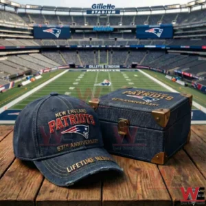 A New England Patriots anniversary cap and matching keepsake box displayed on a wooden table with a football field and stadium seating in the background!