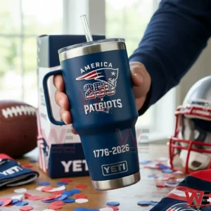 Hand holding a navy blue Patriots America 250 insulated tumbler with handle straw and 1776 2026 text on a table with confetti and football themed background!