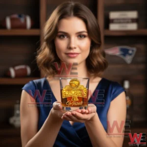 A woman holds a clear whiskey glass with a gold championship badge for New England Patriots centered in focus!