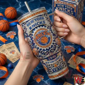 A close view of a New York Knicks tumbler with handle and straw held by hands with Knicks tickets basketballs and logos arranged in the background!