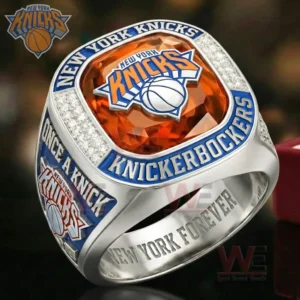 A silver New York Knicks ring with an orange gemstone top featuring the Knicks logo and blue engraved text reading New York Knicks and Knickerbockers with Knicks logos on the sides and New York Forever inside the band!