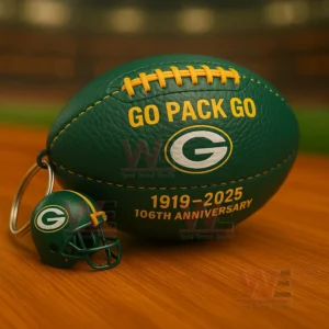 Green Packers football keychain with Go Pack Go text G logo 1919 2025 106th anniversary and a small helmet charm on a wooden tabletop with stadium background!
