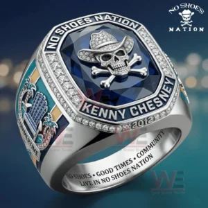 Close up of a silver ring with a faceted blue gemstone face featuring a skull emblem and surrounding diamond accents.