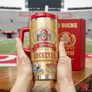 Two hands holding Ohio State Buckeyes one hundred thirty fifth anniversary gold tumbler with red handle and straw featuring Go Bucks Ohio State logo and the years one eight nine zero to two zero two five with a red collector box in the background!
