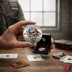 Hand holding a silver Im Old School skull coin with an open display box and playing cards on a wooden table in a rustic setting.