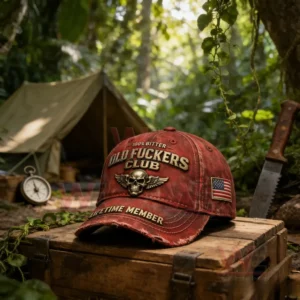 Distressed red baseball cap with embroidered skull wings emblem and bold text on a wooden crate in a forest camping scene with a tent and greenery in the background!