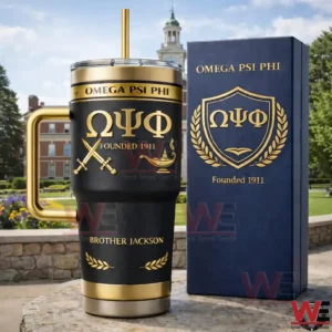 Black and gold Omega Psi Phi tumbler with handle and straw next to a navy gift box with the fraternity crest and Founded 1911 displayed outdoors!