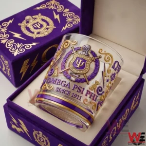 A decorative Omega Psi Phi whiskey glass placed in a purple gift box with gold details and fraternity crest highlighting since nineteen eleven heritage!