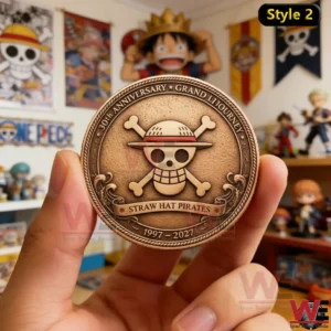 The back side of a One Piece anniversary coin held in hand showing the Straw Hat Pirates emblem with detailed engraving and collector room background!