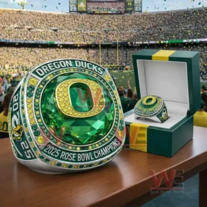 Oregon Ducks 2025 Rose Bowl Champions ring with a large green gemstone center and gold Oregon O logo displayed next to a green and yellow presentation box in a stadium setting!