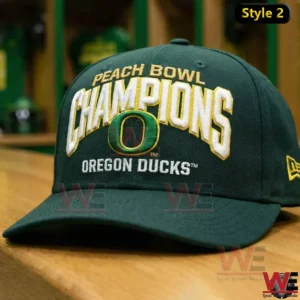 Dark green Oregon Ducks Peach Bowl Champions cap with white gold embroidery and the Oregon O logo displayed on a wooden table in a locker room!