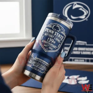 Hands holding a Penn State Nittany Lions 139th anniversary insulated tumbler with navy handle and Beaver Stadium artwork in a room with team themed background.